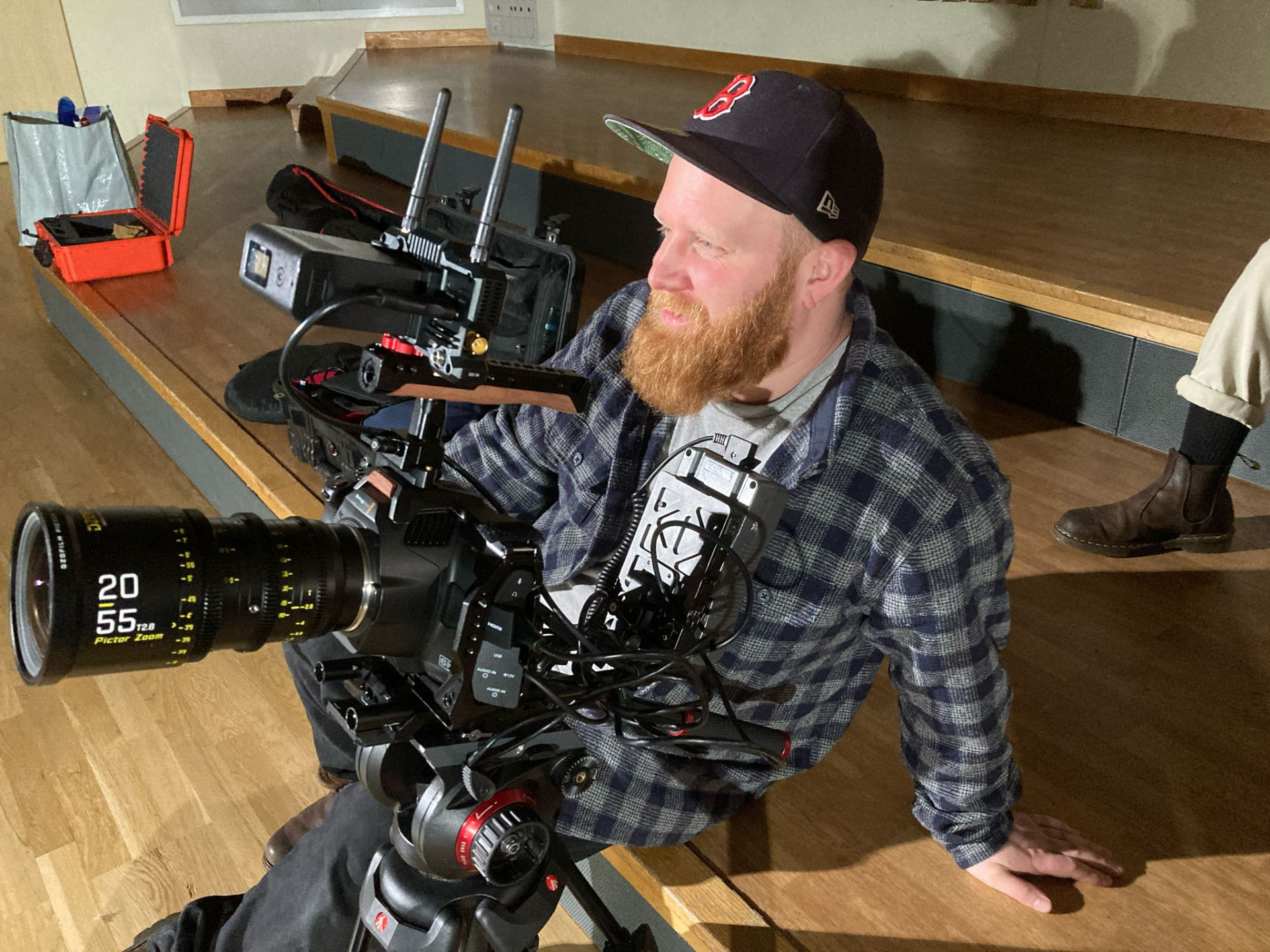 Jack sitting beside a cinema camera rig with a zoom lens